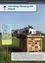 Ein Bild eines hölzernen Insektenhotels mit Moos auf dem Dach steht auf einem Feld. Ein Schild daneben lautet 'Bluhende und summende Steiermark'. Im Hintergrund befindet sich ein modernes Gebäude mit Solarpanelen.