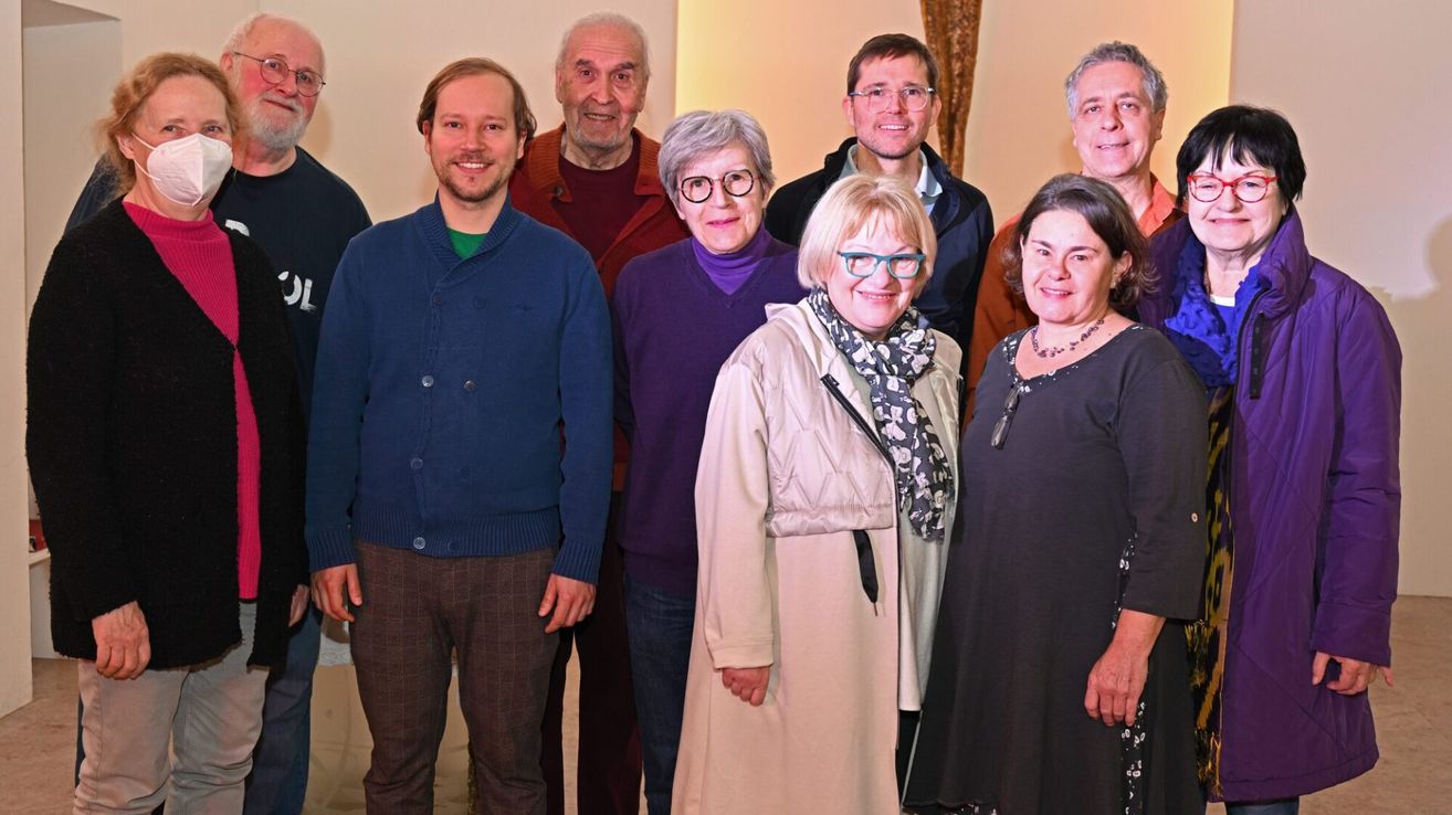 Eine Gruppe von Menschen steht zusammen für ein Foto. Sie lächeln alle und scheinen für eine Kamera zu posieren.