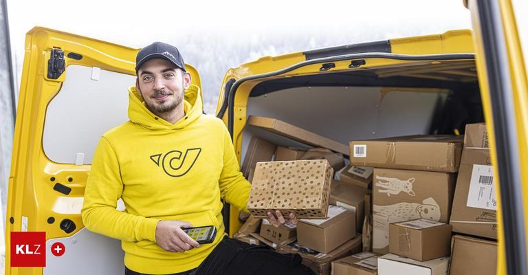 Ein Mann in einer gelben Kapuzenjacke steht neben einem gelben Van, hält eine Box mit Punkten und lächelt in die Kamera, umgeben von vielen Kisten im Van.