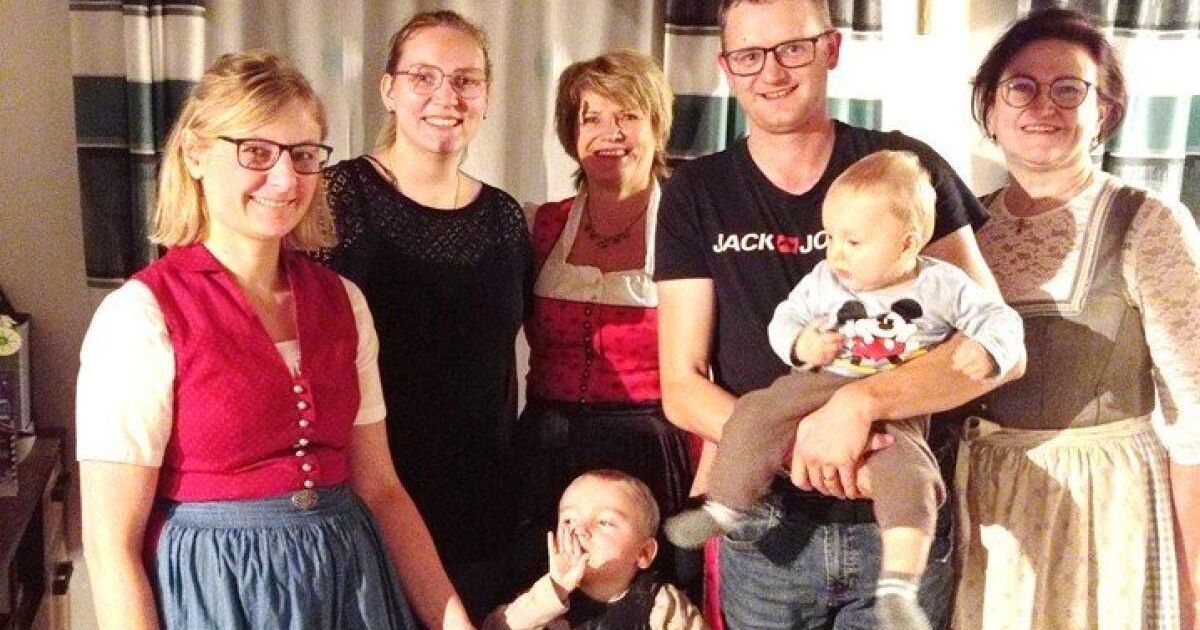 Ein Familienfoto mit fünf Personen, darunter zwei Frauen und drei Männer, einer hält ein Baby, stehen eng beieinander.