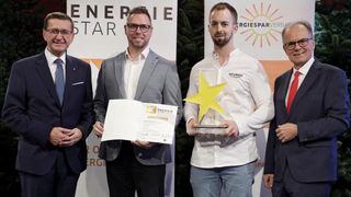 Vier Männer stehen vor einem Banner mit dem Text Energie Star. Der Mann auf der linken Seite hält ein Zertifikat, während der Mann auf der rechten Seite einen gelben Stern hält.