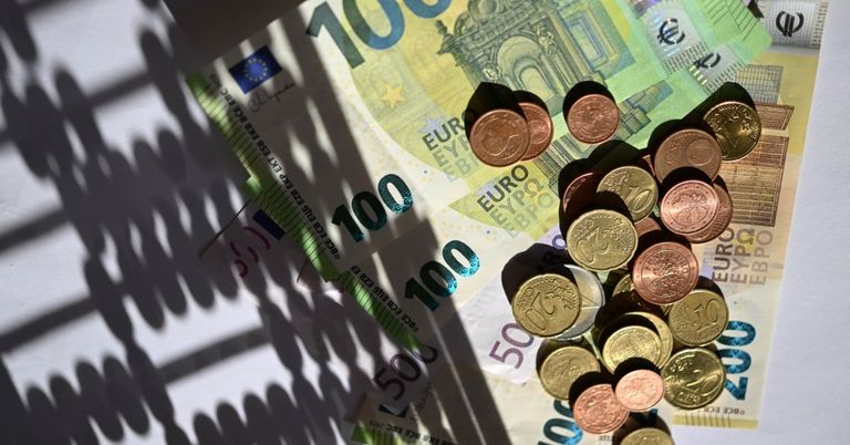 Eine Sammlung verschiedener Euro-Banknoten und Münzen, einschließlich 100, 50 und 20 Euro Scheine, auf einer weißen Oberfläche angeordnet.