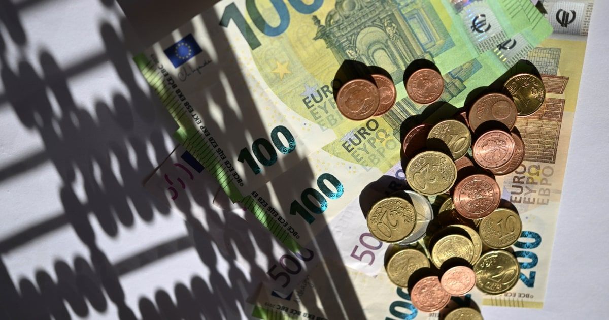 Eine Sammlung verschiedener Euro-Banknoten und Münzen, einschließlich 100, 50 und 20 Euro Scheine, auf einer weißen Oberfläche angeordnet.