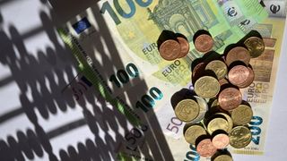Eine Sammlung verschiedener Euro-Banknoten und Münzen, einschließlich 100, 50 und 20 Euro Scheine, auf einer weißen Oberfläche angeordnet.