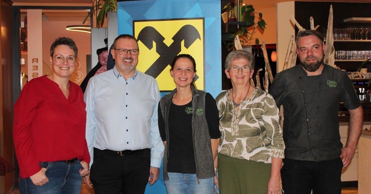 Fünf Personen posieren für ein Foto vor einem gelben und schwarzen X-Zeichen.