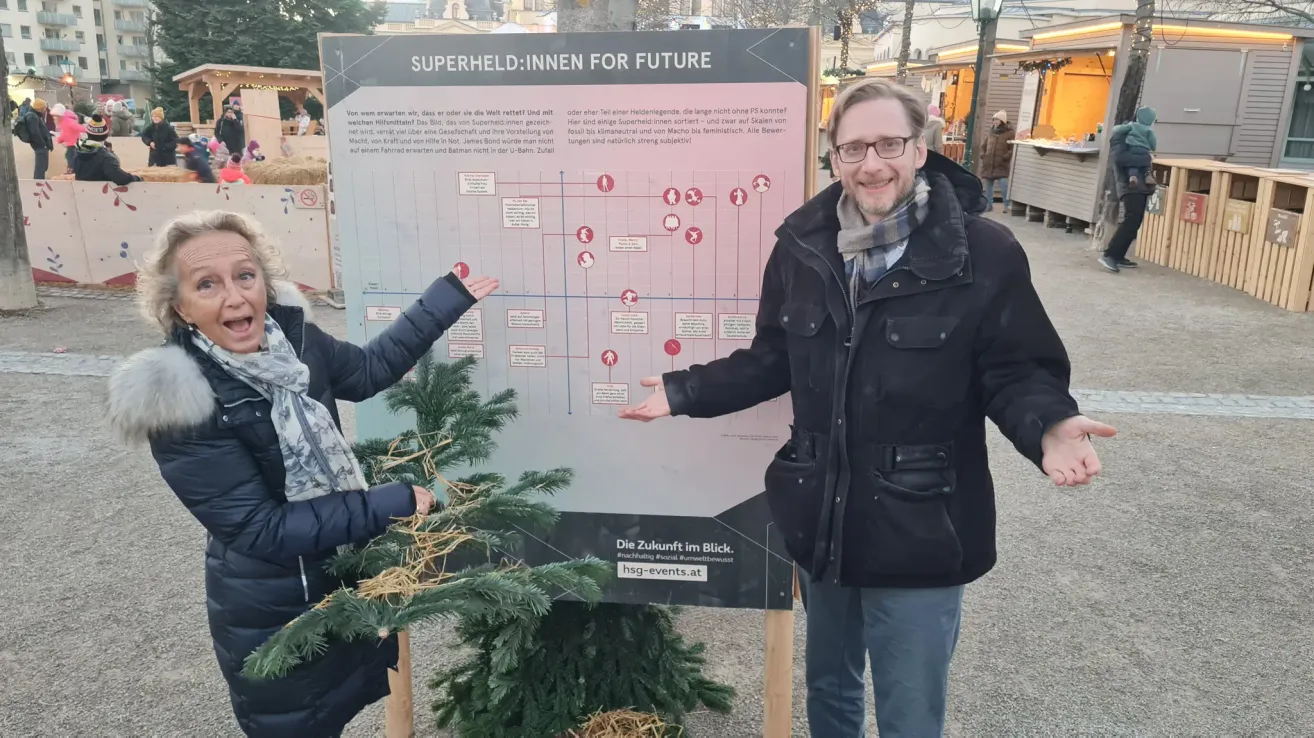 Ein Mann und eine Frau stehen vor einem Schild und diskutieren über die Zukunft von Superhelden. Das Schild enthält ein Flussdiagramm mit Symbolen und Text.