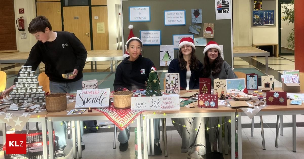 Drei Frauen in Weihnachtsmützen sitzen an einem Tisch mit selbstgemachten Weihnachtsgeschenken und Dekorationen. Ein Schild steht 'Freiwillige Spenden' und ein anderes 'von: 3aC'. Dahinter zeigt eine Wand weihnachtlich gestaltete Poster.