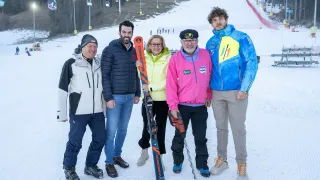 Fünf Personen stehen im Schnee mit Skiausrüstung. Ein Skilift ist im Hintergrund.