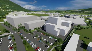 Eine Vogelperspektive einer modernen Industrieanlage mit einem großen Parkplatz, umgeben von Grünflächen und einem Berg im Hintergrund.