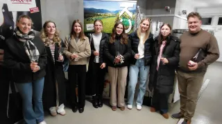 Eine Gruppe von Menschen, darunter Frauen mit Weinglas, posiert für ein Foto in einem Raum mit einem Banner.