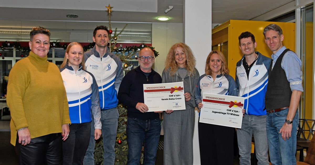 Eine Gruppe von Menschen, die Urkunden halten, posiert für ein Foto vor einem geschmückten Weihnachtsbaum. Der Mann in der Mitte hält eine Urkunde mit einem roten Band.