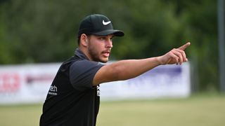 Ein Mann in einer schwarzen Nike-Kappe und -Shirt zeigt mit dem Finger im Freien an einem sonnigen Tag.
