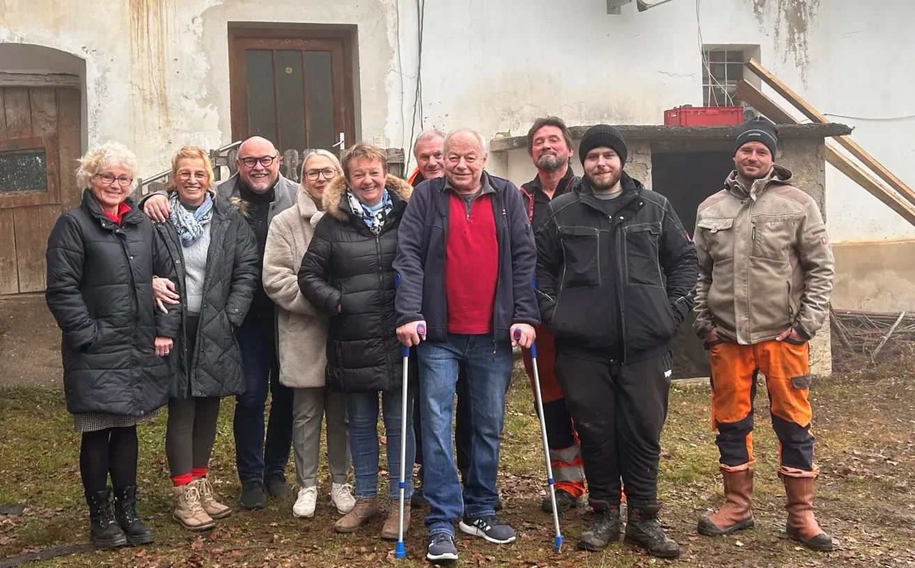 Eine Gruppe von Menschen mit Gehstöcken lächelt für ein Foto vor einem Gebäude.