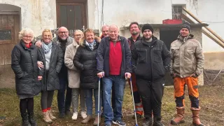 Eine Gruppe von Menschen mit Gehstöcken lächelt für ein Foto vor einem Gebäude.