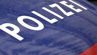 Nahaufnahme eines Polizeiwagens mit dem Wort 'POLIZEI' in weiß auf blauem Hintergrund geschrieben.