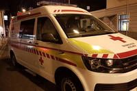 Ein weißer Krankenwagen mit roten Kreuzen an den Seiten und Türen steht an der Straßenseite geparkt.