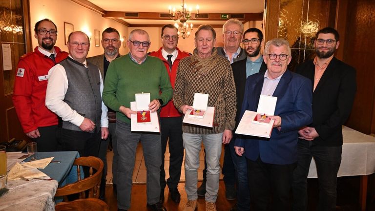 Eine Gruppe von Männern steht zusammen und hält Auszeichnungen, wahrscheinlich bei einer Veranstaltung, wobei ein Mann in Grün Applaus erhält.