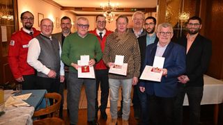 Eine Gruppe von Männern steht zusammen und hält Auszeichnungen, wahrscheinlich bei einer Veranstaltung, wobei ein Mann in Grün Applaus erhält.