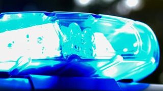 Nahaufnahme eines blauen Notfallfahrzeuglichts, das hell leuchtet und mit einem hellen Schein leuchtet, auf dem Dach eines Fahrzeugs montiert.