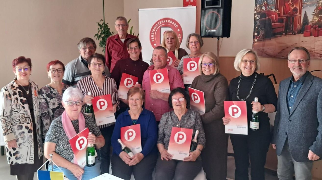 Eine Gruppe älterer Menschen posiert für ein Foto mit roten Plakaten mit einem P-Logo, lächelt und hält Flaschen.