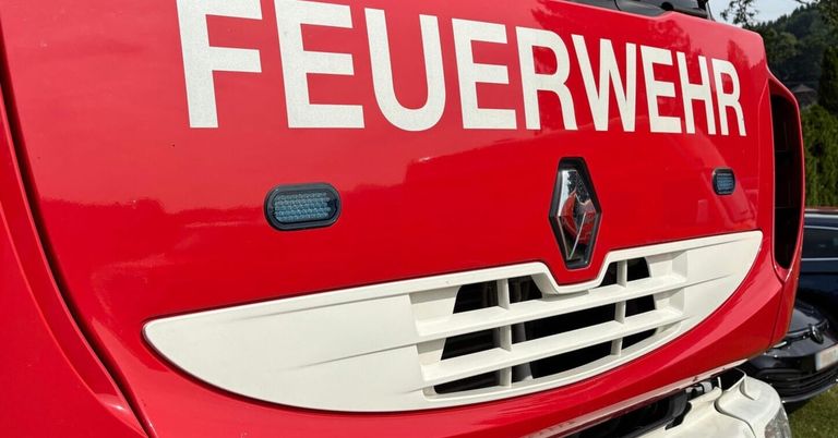 Nahaufnahme der Vorderseite eines roten Feuerwehrwagens, mit dem Wort 'FEUERWEHR' in Weiß, einem roten Renault-Logo und einem Lichtbalken auf der linken Seite.
