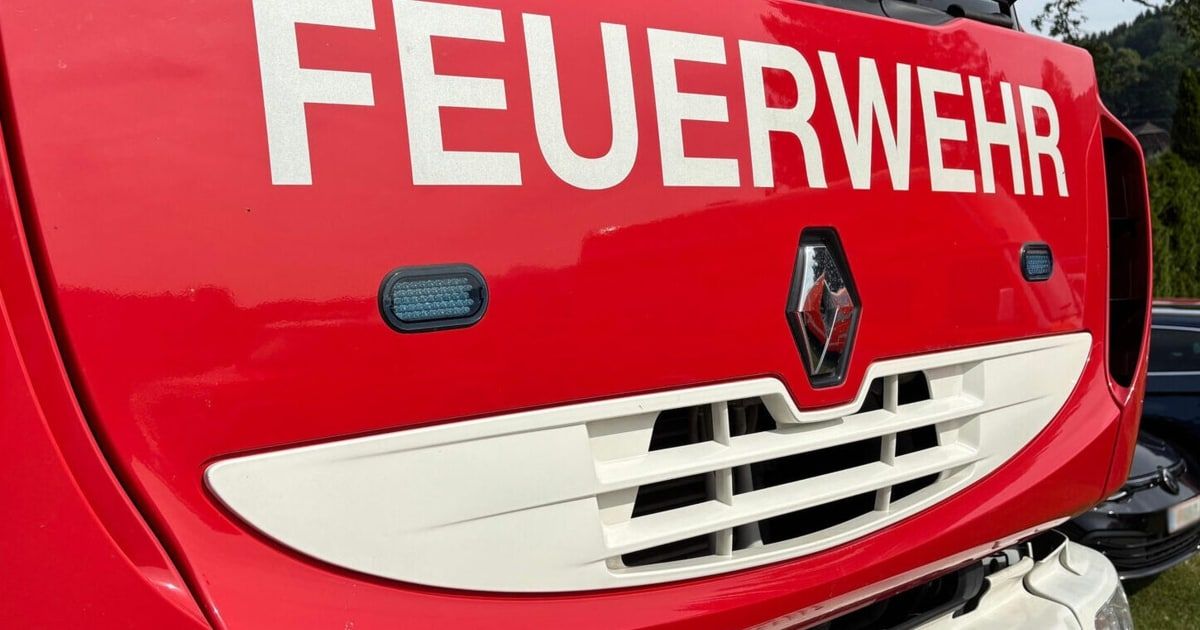 Nahaufnahme der Vorderseite eines roten Feuerwehrwagens, mit dem Wort 'FEUERWEHR' in Weiß, einem roten Renault-Logo und einem Lichtbalken auf der linken Seite.