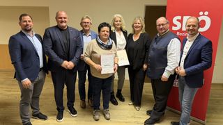 Eine Gruppe von sechs Personen, drei Männer und drei Frauen, steht in einem Raum und hält Urkunden in den Händen. Eine Frau in der Mitte hält eine Urkunde mit 'SPO' darauf.