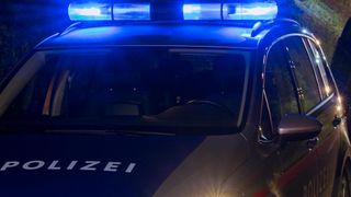 Nahaufnahme eines Polizeiwagens mit blauen Lichtern auf dem Dach und dem Wort 'POLIZEI' an der Seite.