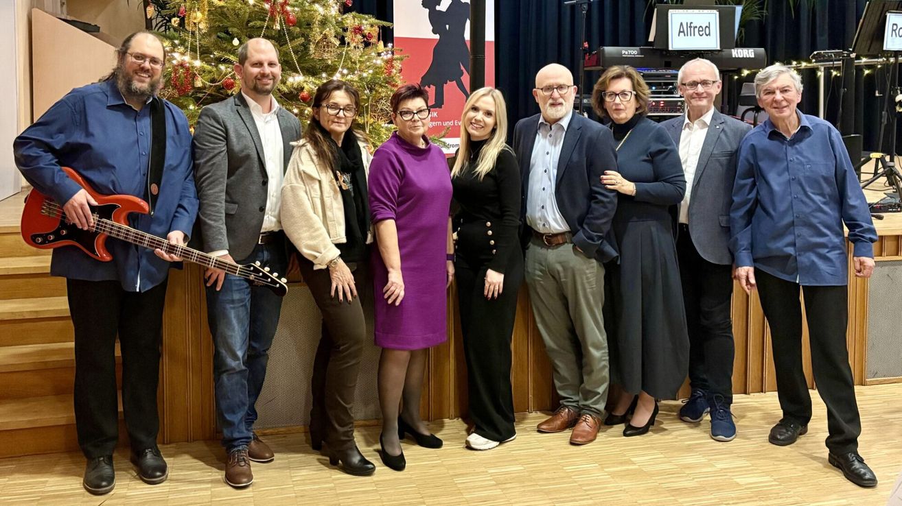 Eine Gruppe von Menschen posiert für ein Foto vor einem geschmückten Weihnachtsbaum.