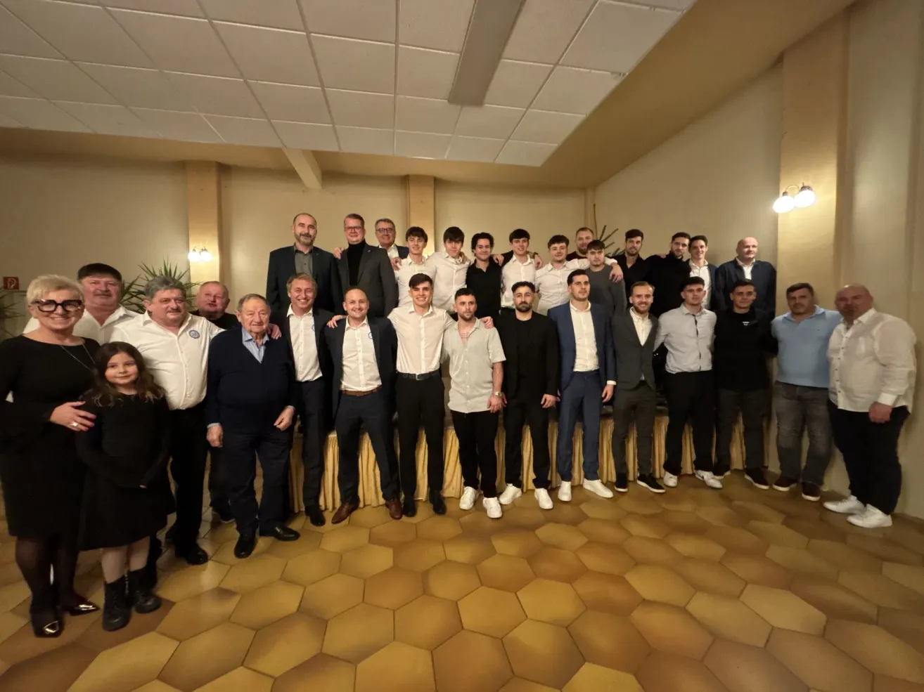 Eine Gruppe von Männern und einem Kind posiert für ein Foto in einem Raum mit einem Sechseck-Fliesenboden.