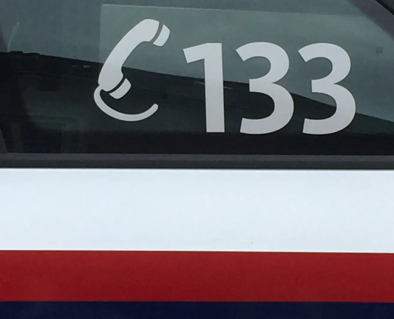 Ein weißes Telefonsymbol mit der Nummer 133 prominent angezeigt. Unter dem Symbol befindet sich ein roter Streifen auf weißem Hintergrund.