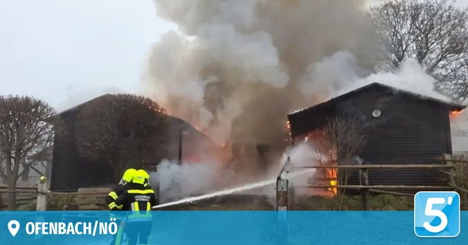 Feuerwehrleute bekämpfen ein Feuer in einer Scheune in der Stadt Offenbach. Rauch und Flammen dringen aus der Struktur aus.
