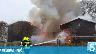 Feuerwehrleute bekämpfen ein Feuer in einer Scheune in der Stadt Offenbach. Rauch und Flammen dringen aus der Struktur aus.