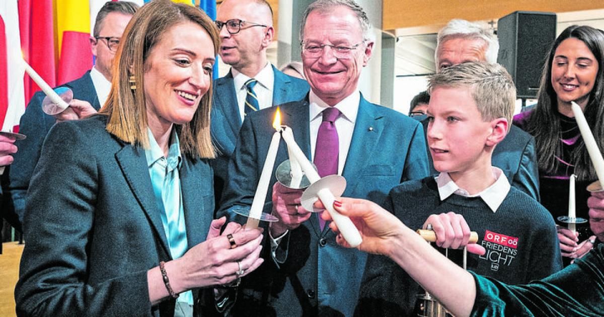 Eine Gruppe von Menschen hält brennende Kerzen bei einer Veranstaltung. Eine Frau und ein Junge lächeln. Dahinter schauen zwei Männer in die Kamera.