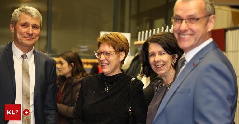 Zwei Frauen und ein Mann lächeln vor einem Regal mit weißen Kerzen, während eine andere Frau und ein Mann hinter ihnen stehen.