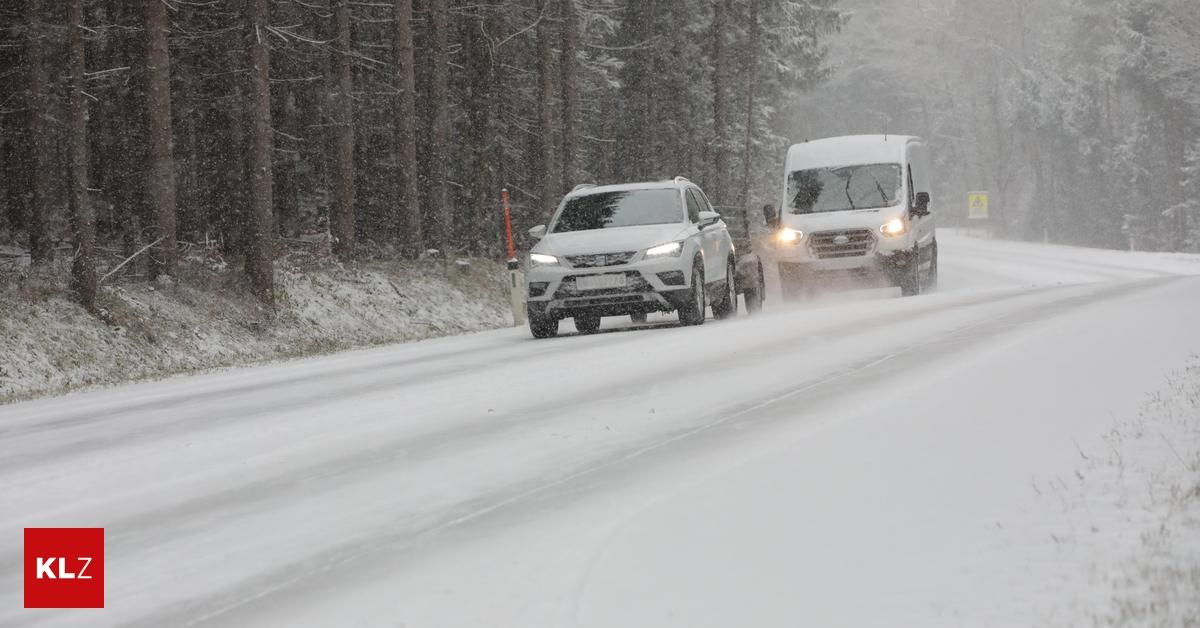 Eine verschneite Straße mit zwei fahrenden Fahrzeugen. Das Auto hat Scheinwerfer eingeschaltet und der Van hat ein Logo an der Seite.