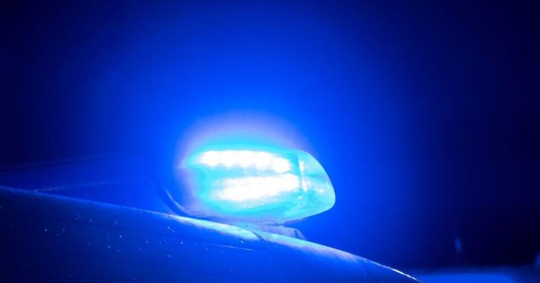 Ein blaues Licht auf einem Auto blinkt, wahrscheinlich von einem Polizeifahrzeug. Das Licht spiegelt sich auf der Oberfläche des Autos.