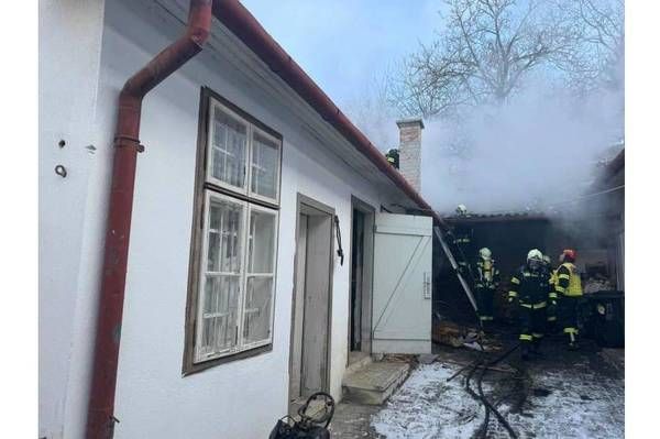 Feuerwehrleute arbeiten daran, ein Feuer in einem Haus zu löschen, wobei Rauch aus dem Dach kommt.