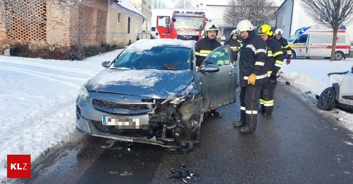 Ein beschädigtes Auto mit Feuerwehrleuten und einem Feuerwehrwagen in der Nähe. Die Front des Autos ist stark beschädigt, und Schnee bedeckt das Auto und den Boden.