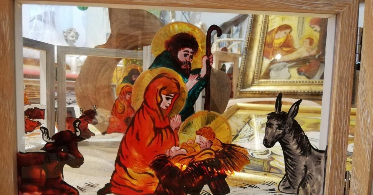 Ein Glasbild zeigt die Weihnachtsszene mit Maria, Josef und dem Jesuskind, zusammen mit anderen Figuren und einem Esel in einer Vitrine.