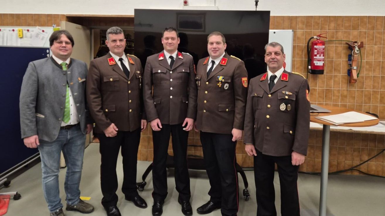 Vier Männer in Militäruniformen stehen lächelnd und schauen in die Kamera zusammen in einem Raum.