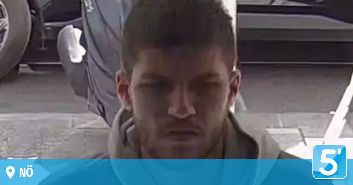 Ein Mann mit kurzen Haaren und einer grauen Kapuze sitzt in einem Raum, die Augen geschlossen, er sieht ernst oder nachdenklich aus.