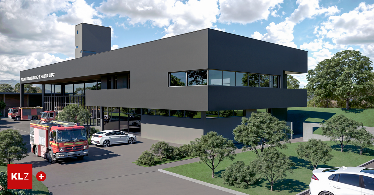 Ein modernes Gebäude mit grauer Außenseite, großen Fenstern und einem vor dem Gebäude geparkten Auto. Bäume und ein Feuerwehrauto sind ebenfalls vorhanden.