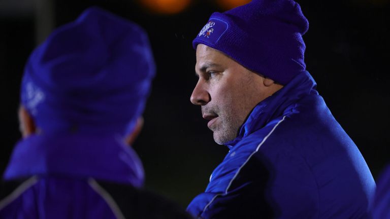 Ein Mann in einer blauen Jacke und Mütze schaut jemanden an, wahrscheinlich bei einer Sportveranstaltung.