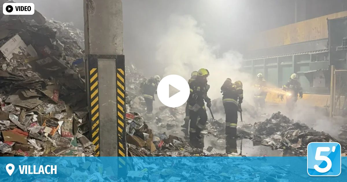 Feuerwehrleute in Schutzkleidung arbeiten an einem rauchenden Schutthaufen mit Werkzeugen. Rauch steigt vom Boden auf. Ein weißer Kreis mit einer Linie befindet sich in der Mitte.
