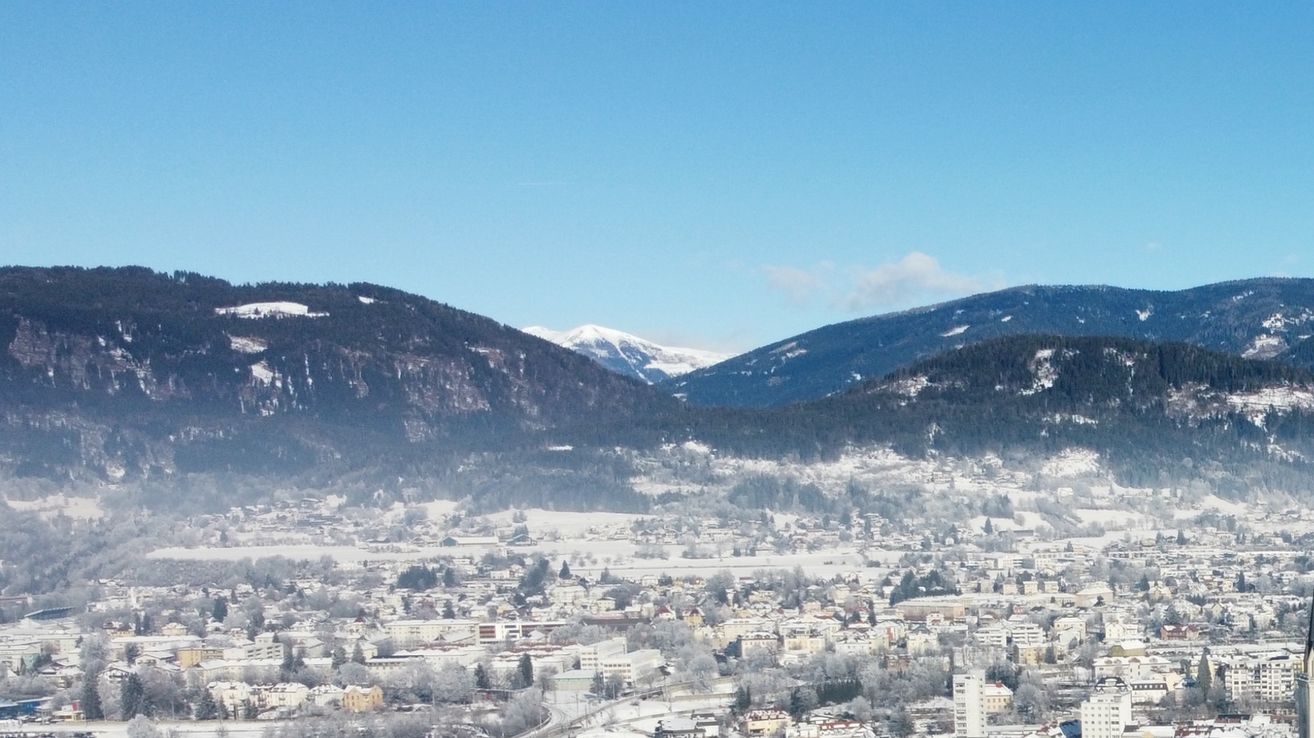 Aerial view of a town covered in snow with mountains in the background under a clear blue sky.