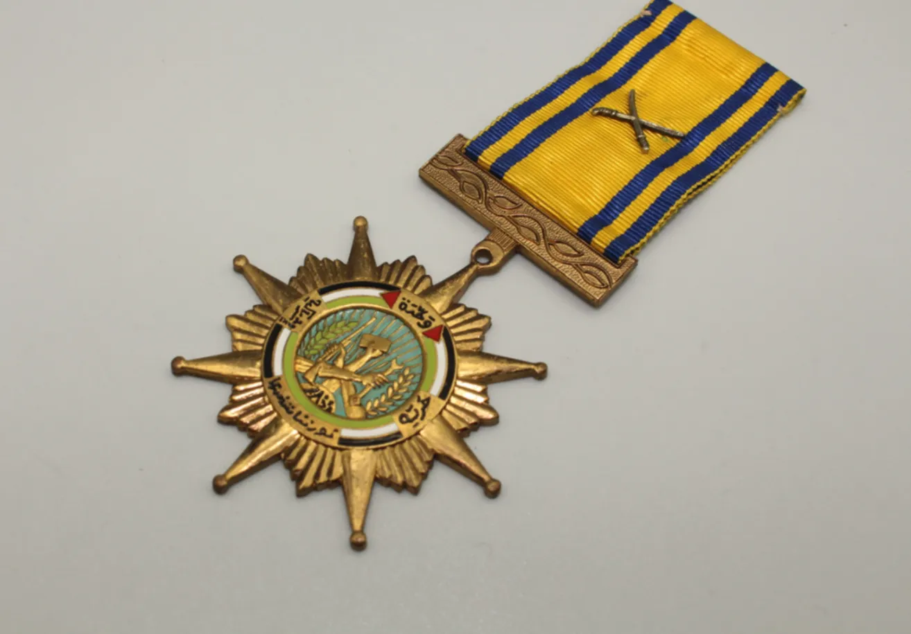 A gold star medal with a yellow and blue ribbon is displayed. The star has a green circle with a soldier and wheat sheaf in the center.