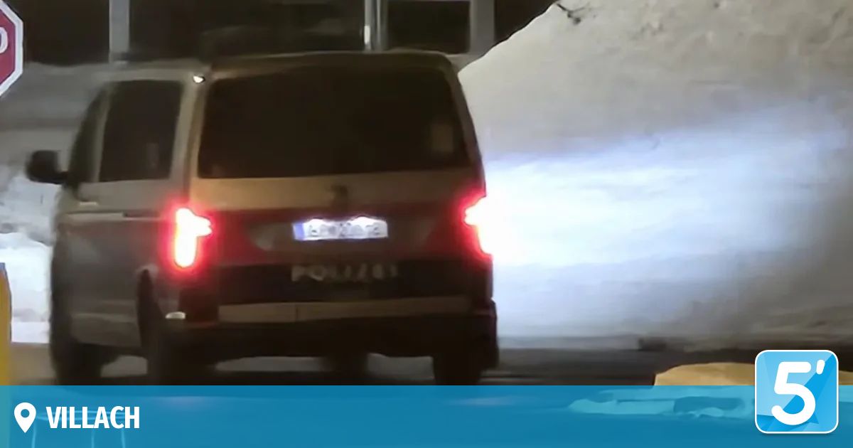 A rear view of a vehicle with illuminated brake lights, parked in a snowy area. The license plate is partially visible.