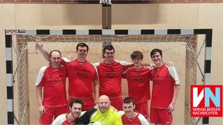 A group of men in red uniforms with white accents are posing for a photo in front of a net.