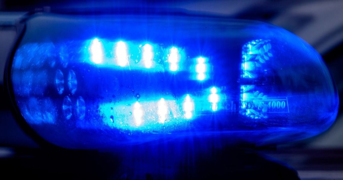 Nahaufnahme einer blauen Notfall-Fahrzeugleuchte, die mehrere blaue Lichter in einem Gittermuster zeigt, nass vom Regen.